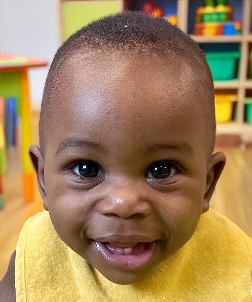 A joyful infant smiles brightly, showcasing happiness and curiosity in a nurturing environment.