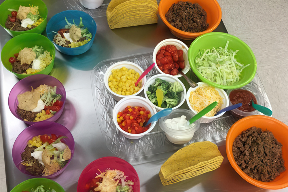 A vibrant taco bar with seasoned meat, toppings like lettuce and tomatoes, served in colorful bowls.