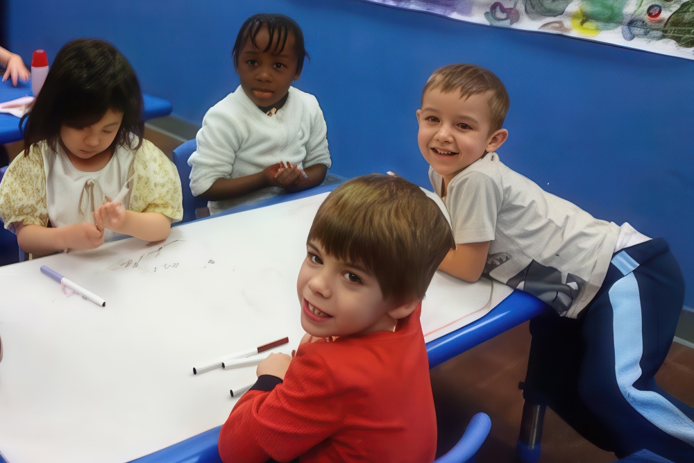 Four children gather around a table, smiling and engaged in drawing with markers, enjoying a creative moment together.