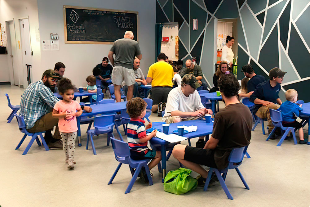 A indoor scene with adults and children at tables, all engaged in various activities and enjoying their time together.