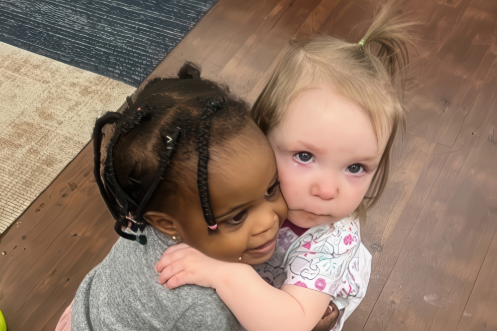 Two young children share a warm embrace, smiling and showing affection for each other.