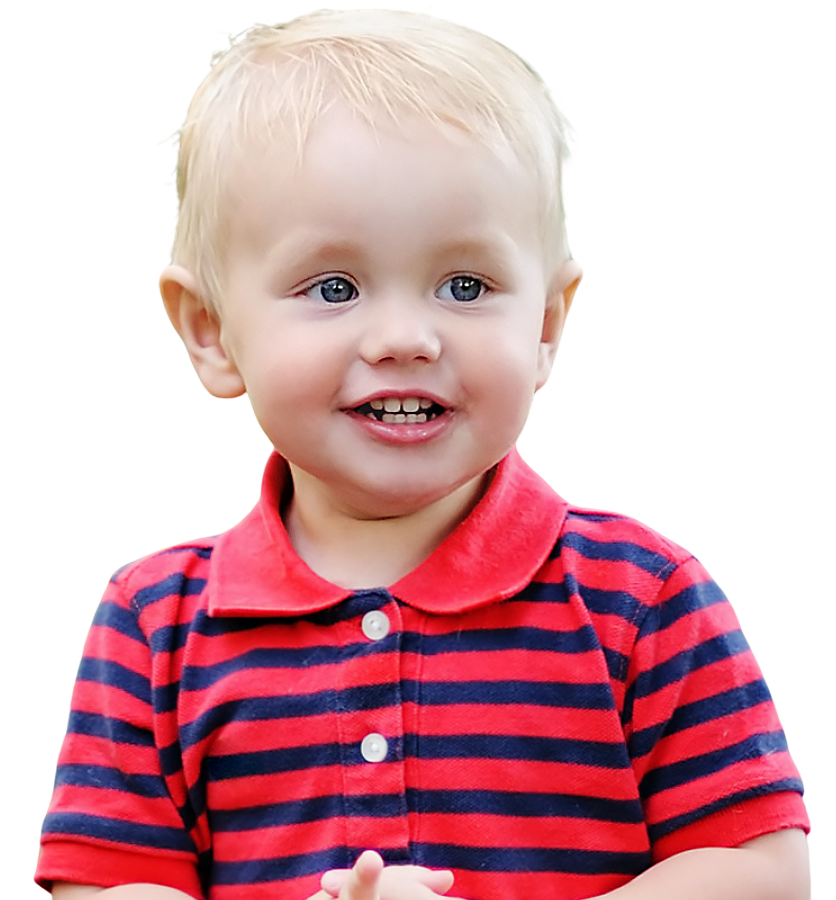 A happy young child stands with a bright smile, wearing a red and blue striped shirt.