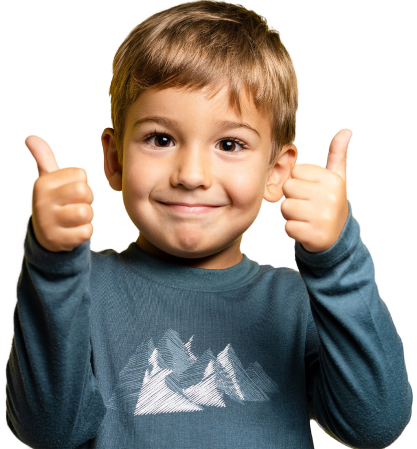 A young boy smiles widely, giving two thumbs up, exuding happiness and enthusiasm.